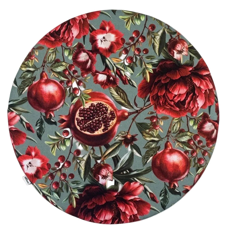 Mantel individual redondo reversible de algodón con estampado floral de granadas en tonos rojos y fondo verde agua. Diseño elegante y original para vestir la mesa con personalidad.