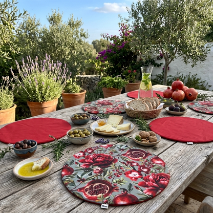 Mesa exterior con pack de manteles individuales redondos reversibles de algodón, estampado floral de granadas en tonos rojos y reverso rojo. Manteles elegantes y originales para vestir la mesa con personalidad y sobremesas especiales.