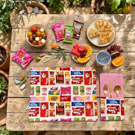 Pack de 2 servilletas con bolsillo para cubiertos en algodón 100%, con estampado inspirado en chocolatinas y diseño reversible. Un detalle divertido y funcional para mesas con personalidad, perfecto para sobremesas bonitas, regalos originales y mesas con mucho carácter.