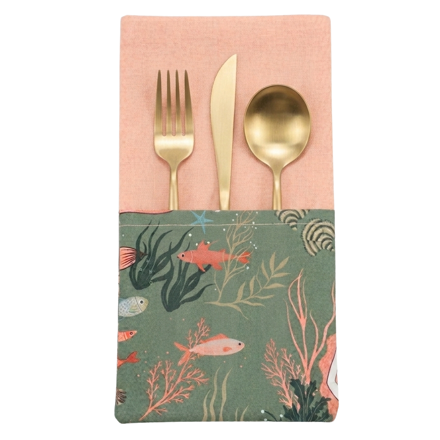 Servilleta con bolsillo introducir para cubiertos. Color melocotón con bolsillo estampado de sirenas, corales y peces en tonos melocotón y verdes. reversible en tono melocotón.