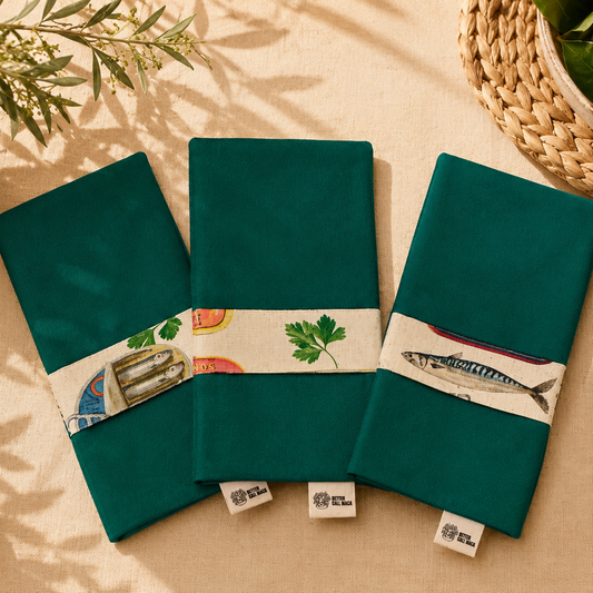 servilleta con guardascubiertos en tejido de algún verde reversible y tira en ella estampada de algodon beige con dibujos de sardinas y latas