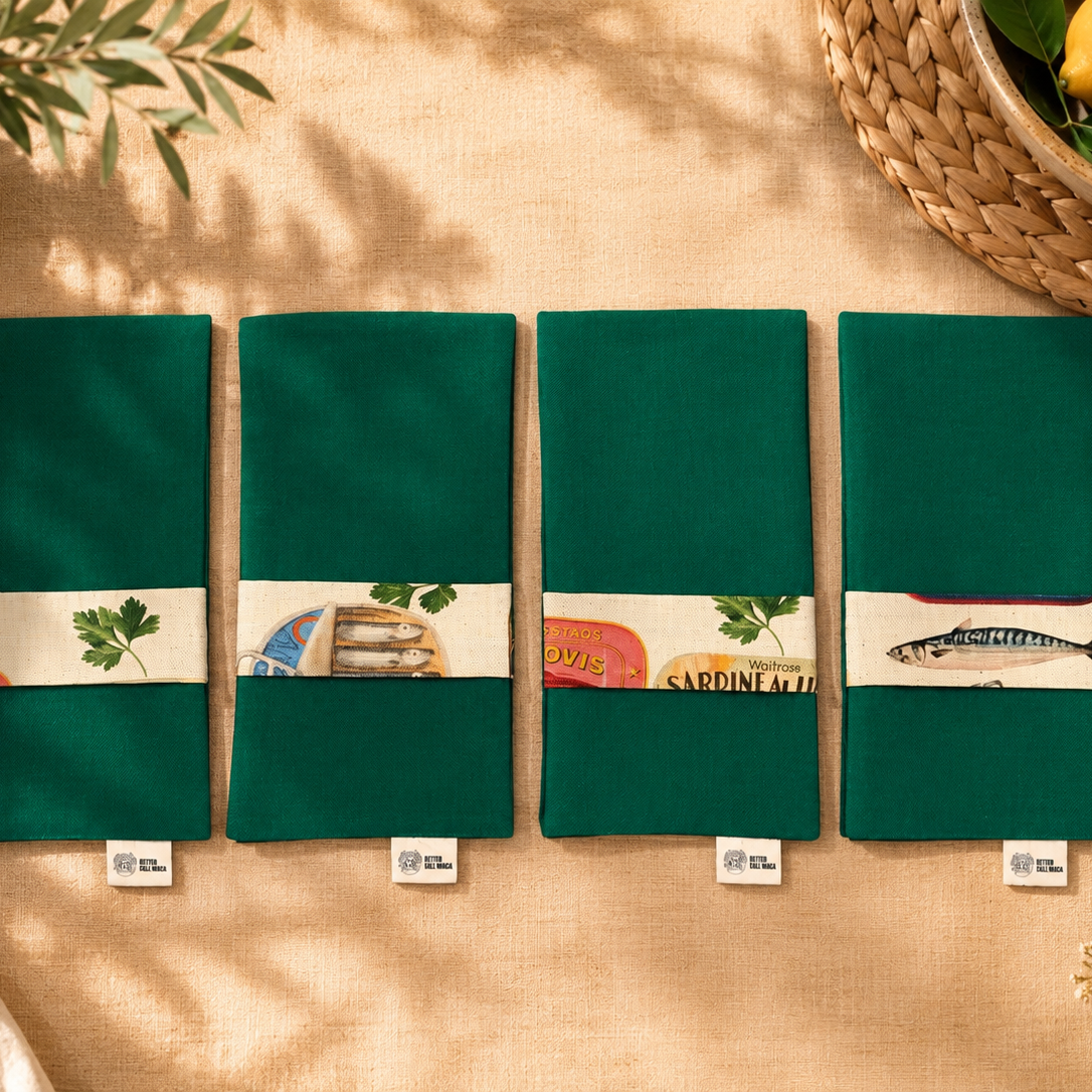 servilleta con guardascubiertos en tejido de algún verde reversible y tira en ella estampada de algodon beige con dibujos de sardinas y latas